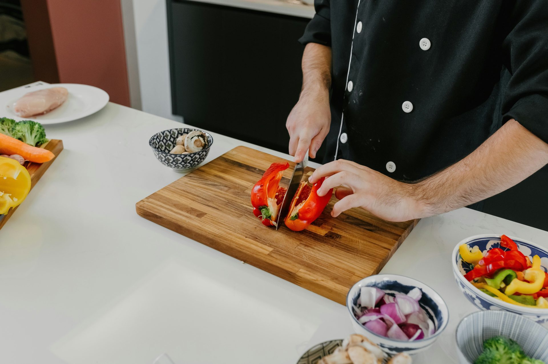 A man cutting up a sandwich on top of a wooden cutting board